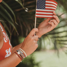 Load image into Gallery viewer, Girl holding the American flag and wearing the small  Brave K&#39;lani hair tie and bracelet.
